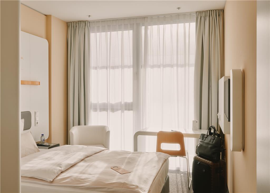 Single room with a desk, a chair, club chair and tv.