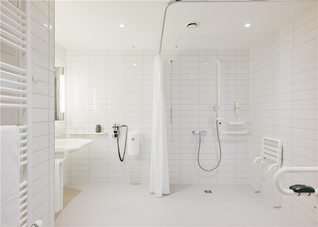 Handicapped bathroom with (sitting) shower and wheelchair-accessible washbasin