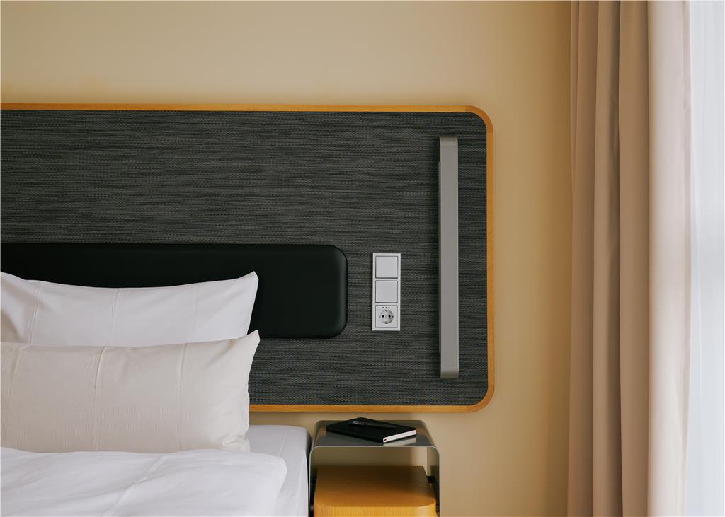 Bed with two pillows, grey headboard and a sidetable