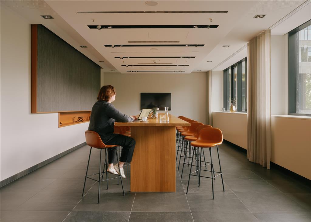 One of the two separate rooms of our UPPER DECK bar featuring a long table, bar stools, a TV and modern décor