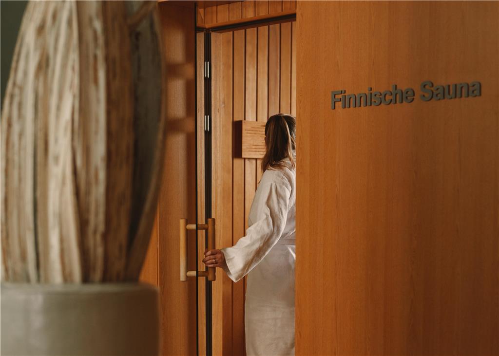 Guest in a bathrobe enters a Finnish sauna