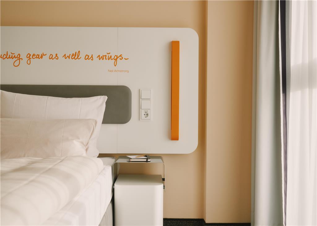 Bed with a white headboard and a quote written on it. Sidetable with a notebook on top.